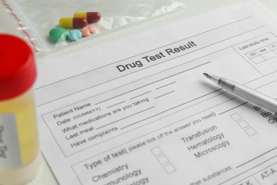 Photo of Drug test result form, pills and container with urine sample on light table, closeup
