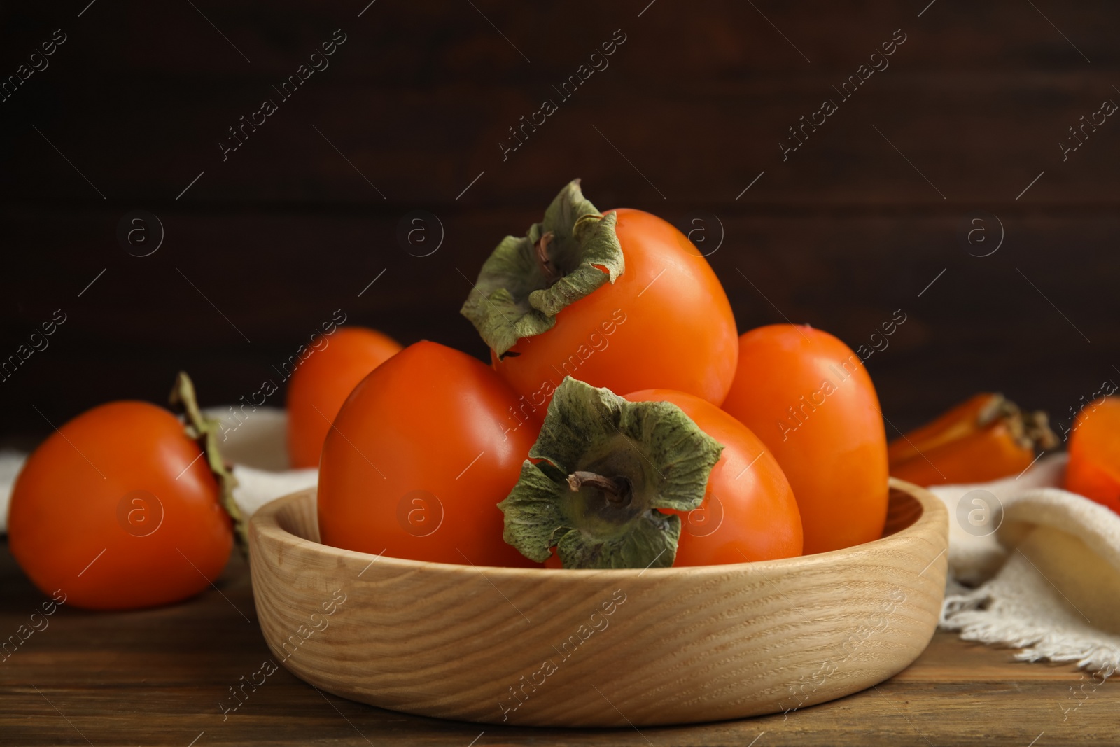 Photo of Tasty ripe persimmons on wooden table, closeup