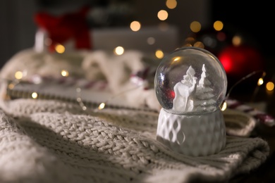 Christmas snow globe with knitting clothes on blurred background. Space for text