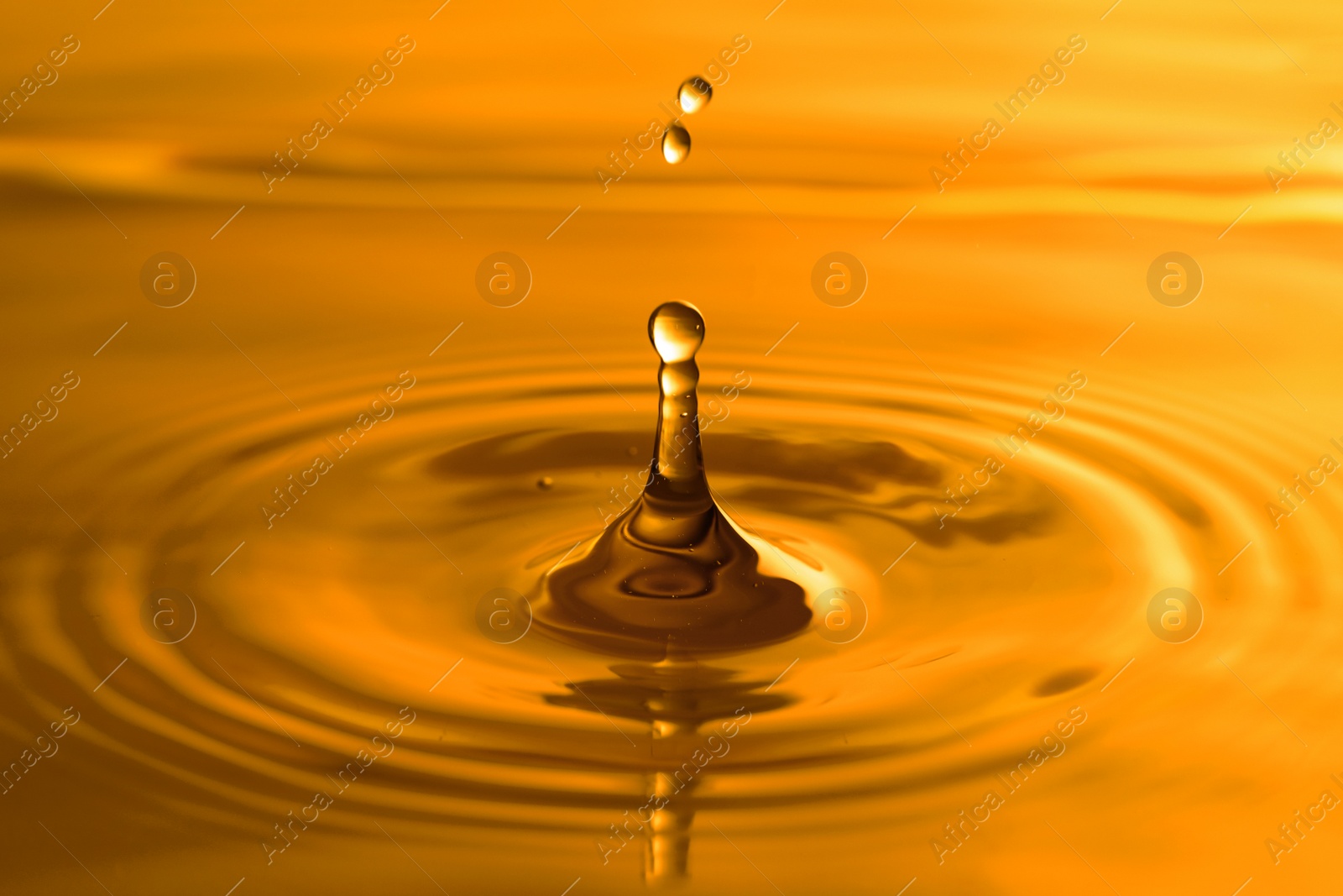 Image of Splash of golden oily liquid with drops as background, closeup