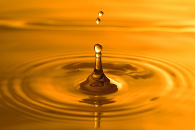 Splash of golden oily liquid with drops as background, closeup