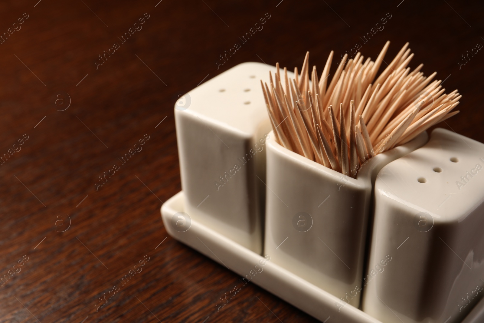 Photo of Holder with salt, pepper and toothpicks on wooden table, closeup. Space for text