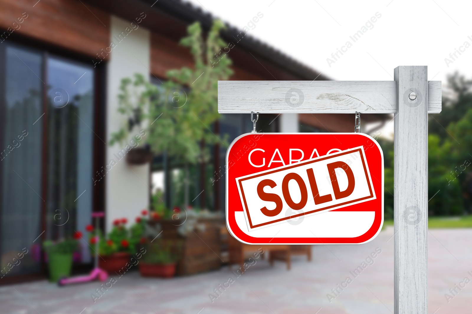 Image of Garage sale sign with Sold sticker near house