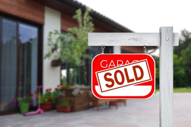 Image of Garage sale sign with Sold sticker near house