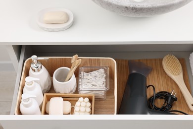 Different bath accessories and personal care products in drawer indoors