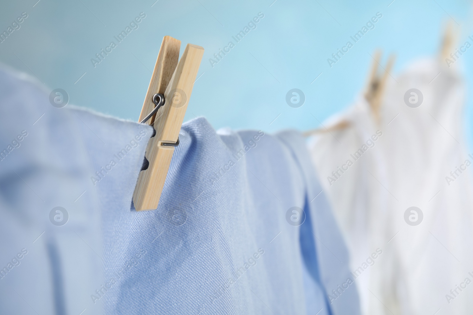 Photo of Washing line with wooden clothespin and garment against blurred background, closeup