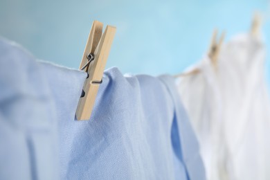 Photo of Washing line with wooden clothespin and garment against blurred background, closeup