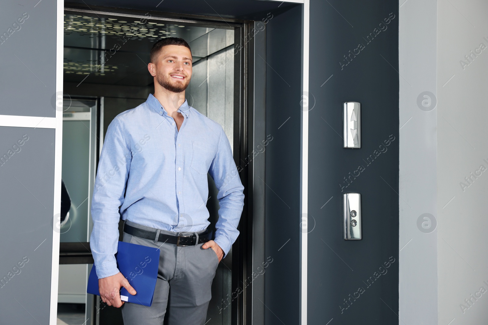 Photo of Attractive young businessman walking out modern elevator