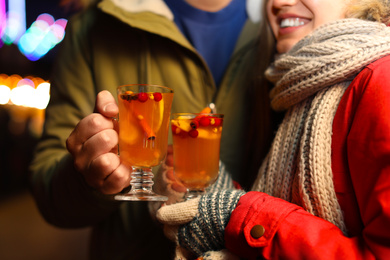 Photo of Happy couple with mulled wine at winter fair, closeup