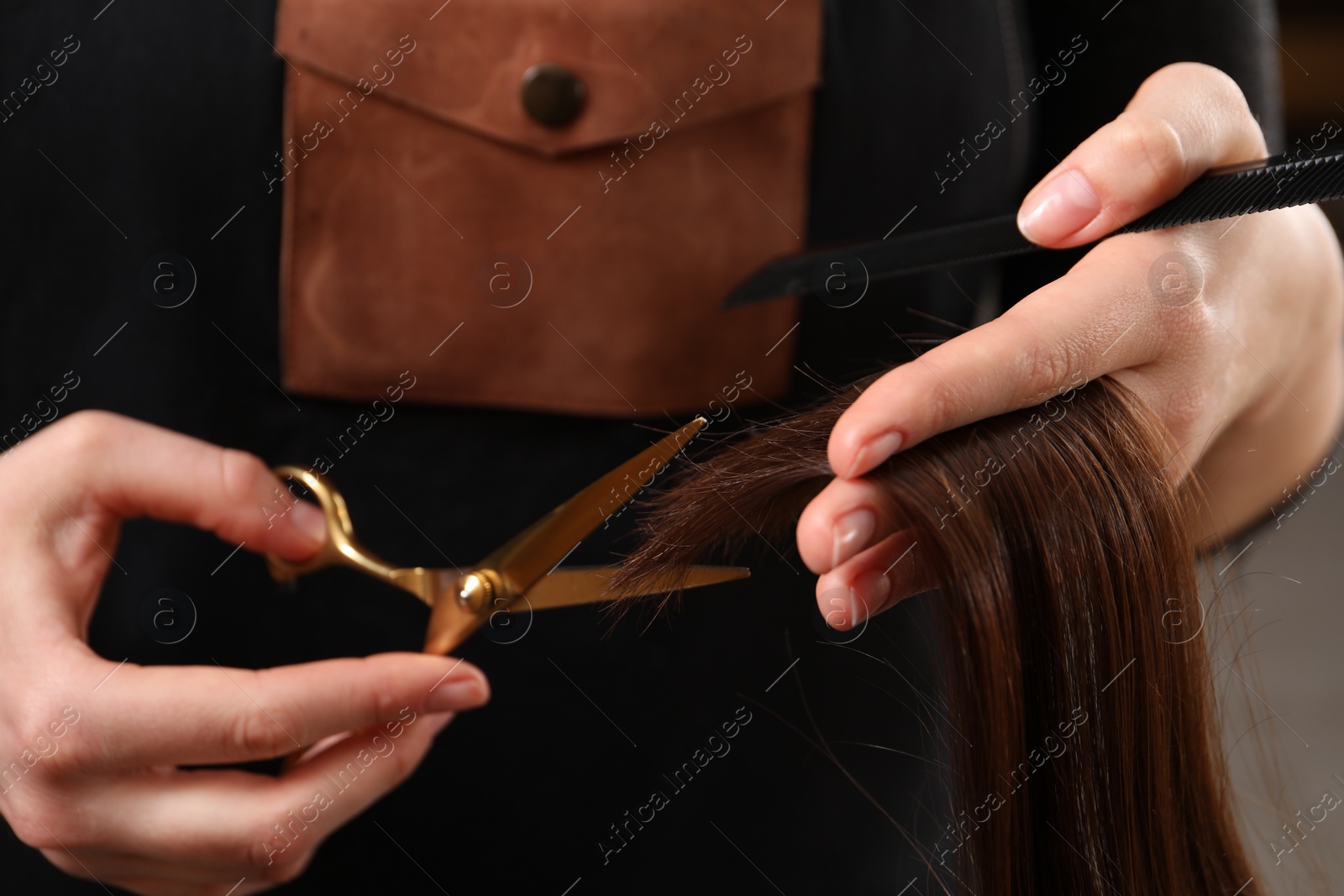 Photo of Hairdresser cutting client's hair with scissors in salon, closeup