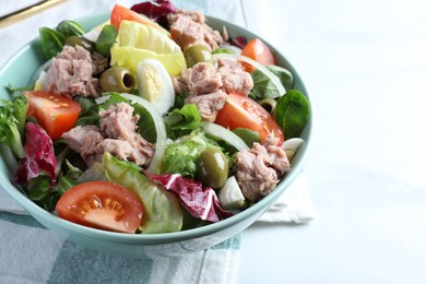 Photo of Bowl of delicious salad with canned tuna and vegetables on white table, closeup. Space for text