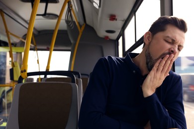 Sleepy tired man yawning in public transport