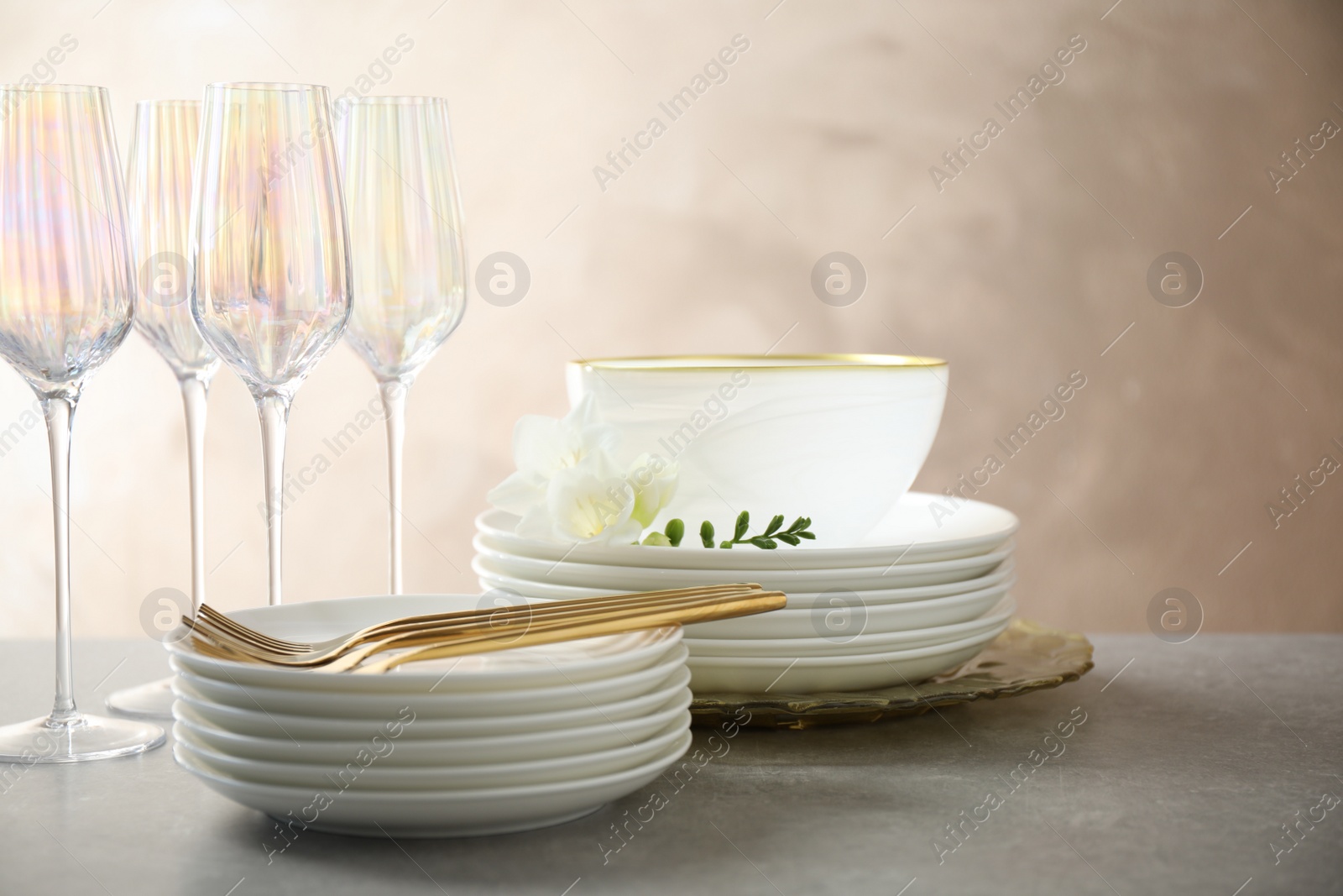 Photo of Set of glasses and dishes with flowers on light grey table