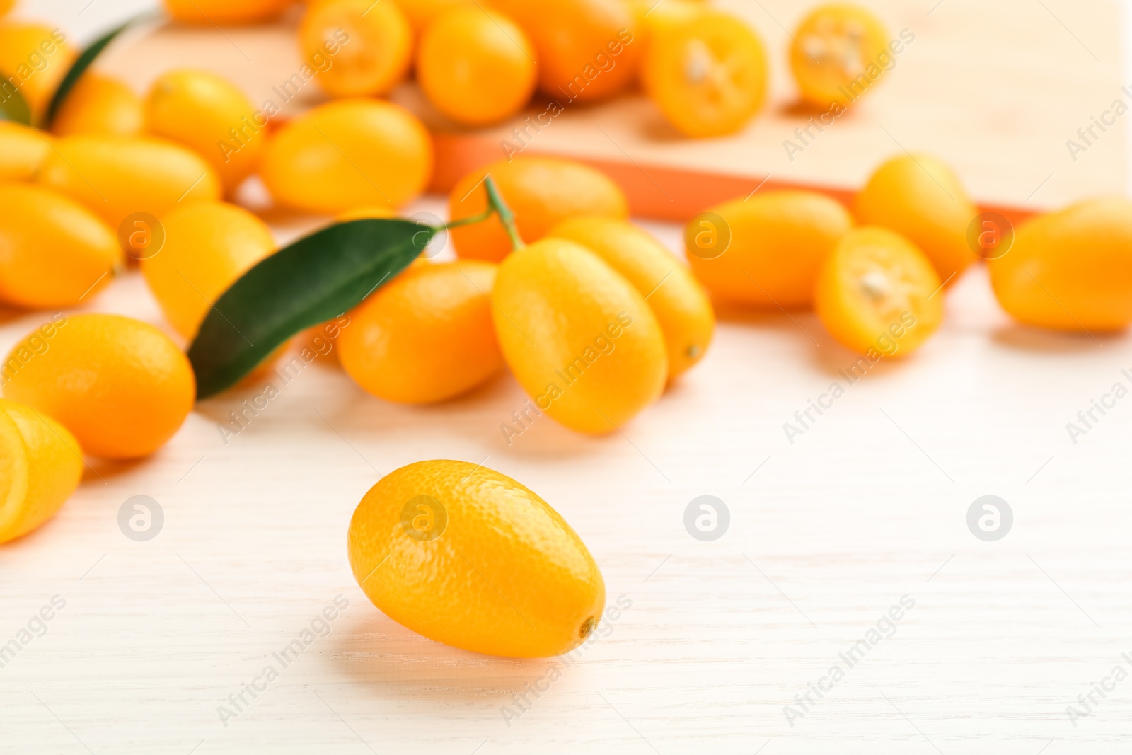 Photo of Fresh ripe kumquats on white wooden table, closeup