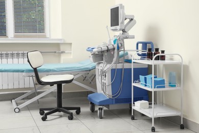 Photo of Ultrasound machine, chair, medical trolley and examination table in hospital