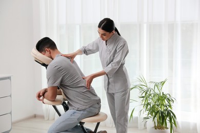Photo of Man receiving massage in modern chair indoors