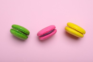 Photo of Delicious colorful macarons on pink background, flat lay