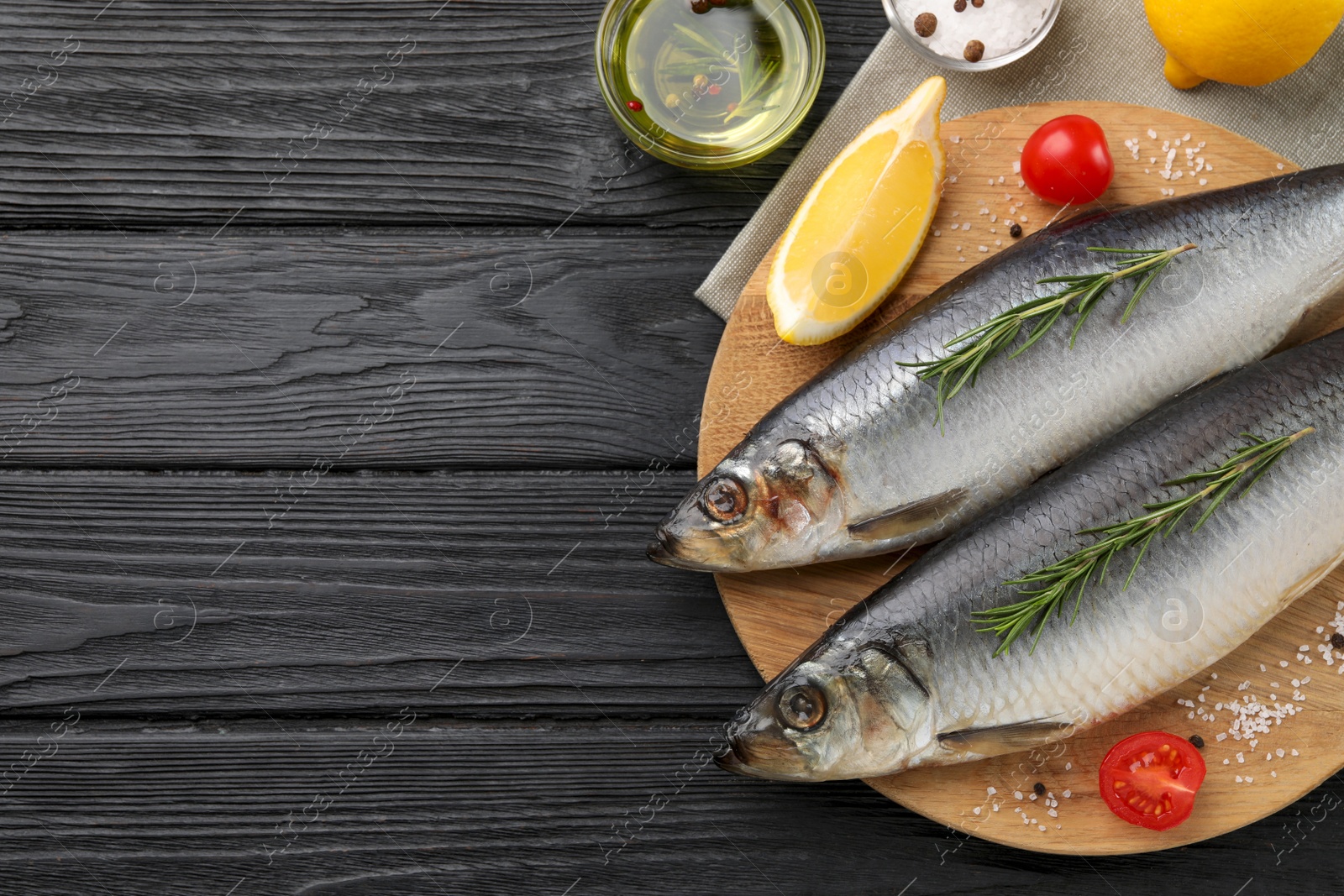 Photo of Delicious salted herrings and ingredients on black wooden table, flat lay. Space for text