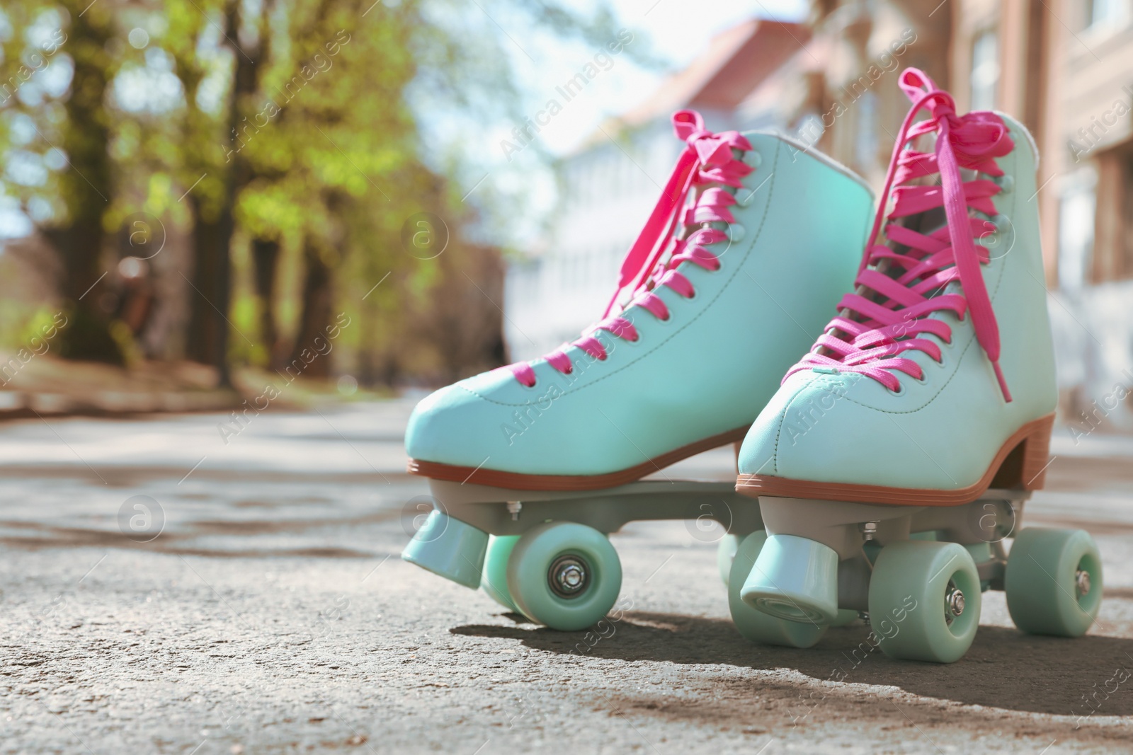 Photo of Stylish pink roller skates outdoors on sunny day. Space for text