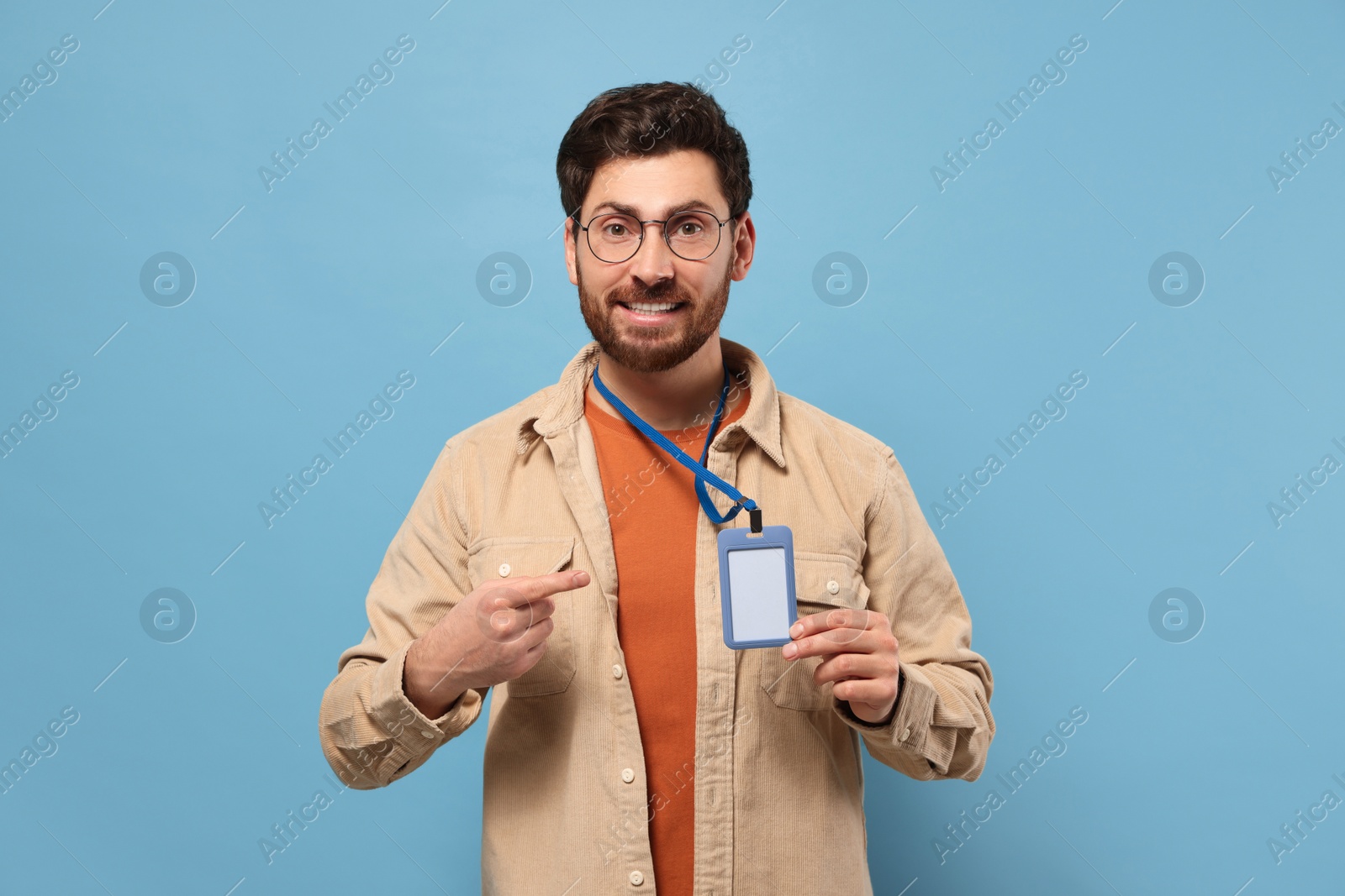 Photo of Smiling man showing VIP pass badge on light blue background