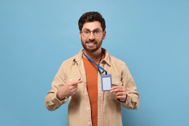 Photo of Smiling man showing VIP pass badge on light blue background