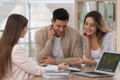 Travel agent consulting clients at table in office