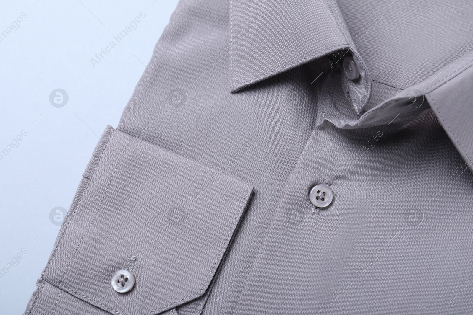 Photo of Stylish grey shirt on white background, closeup. Dry-cleaning service