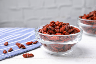 Photo of Dried goji berries on white wooden table, closeup