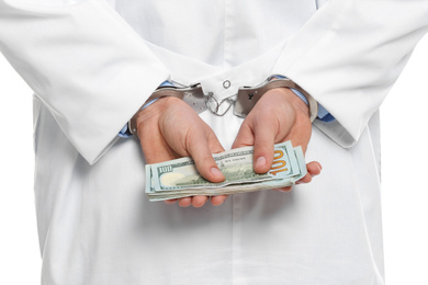 Doctor in handcuffs with bribe on white background, closeup. Corrupted medicine