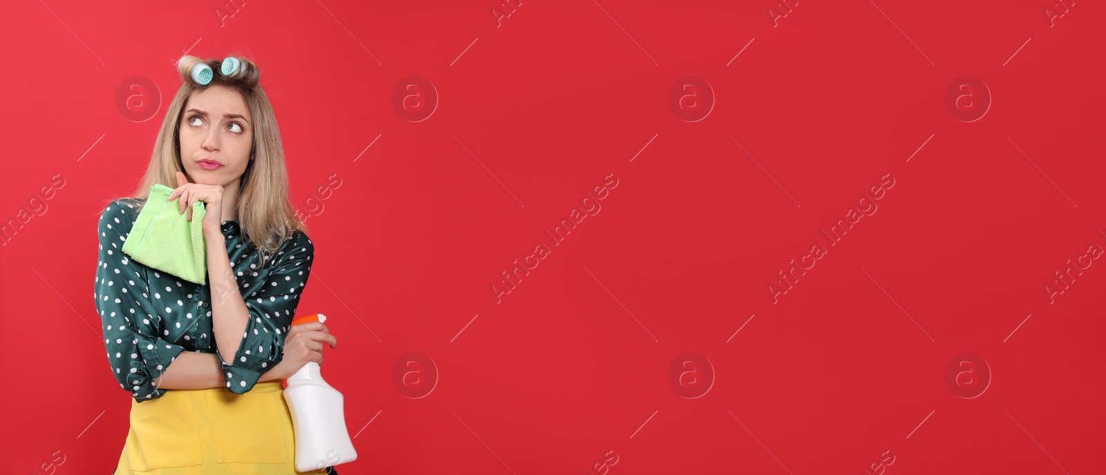 Photo of Young housewife with detergent and rag on red background. Space for text