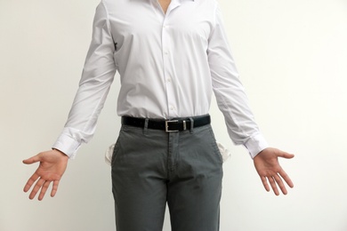 Photo of Businessman showing empty pockets on light background, closeup