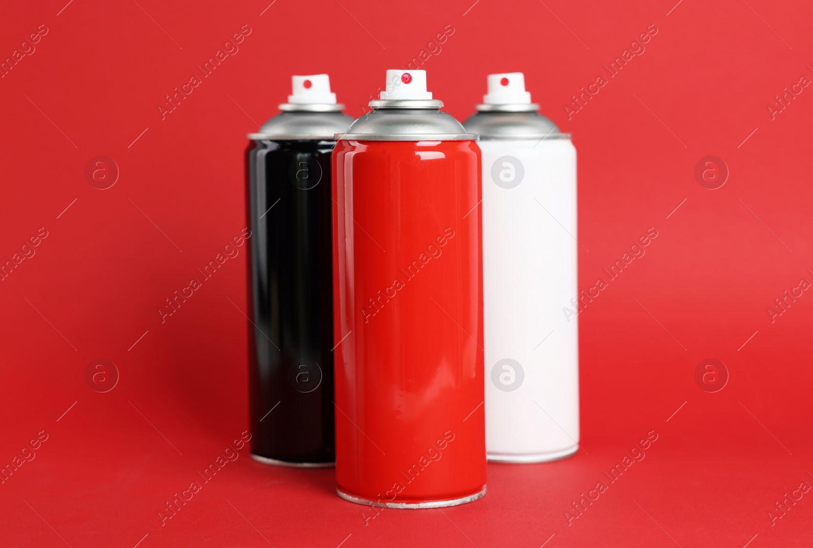 Photo of Colorful cans of spray paints on red background