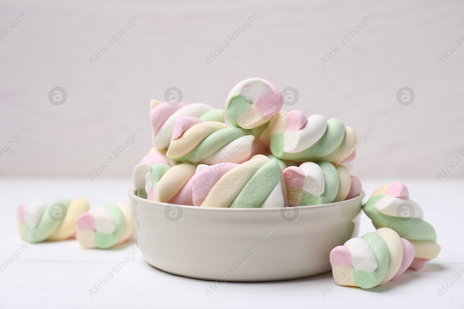 Photo of Bowl with colorful marshmallows on white table, closeup