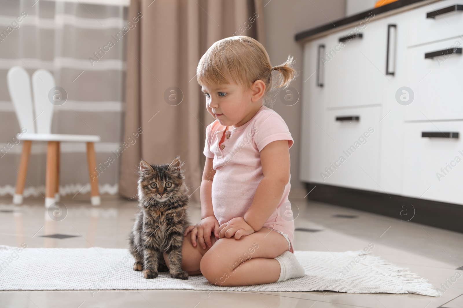 Photo of Cute little child with adorable pet on floor at home