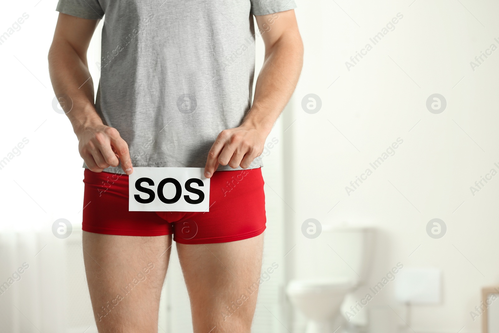 Photo of Man holding SOS sign indoors, space for text. Urology problems