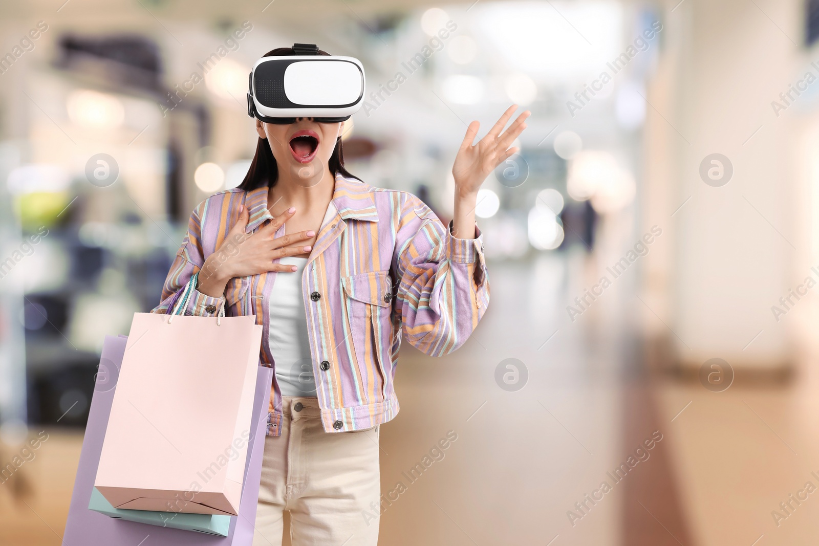 Image of Young woman with shopping bags using virtual reality headset in simulated store