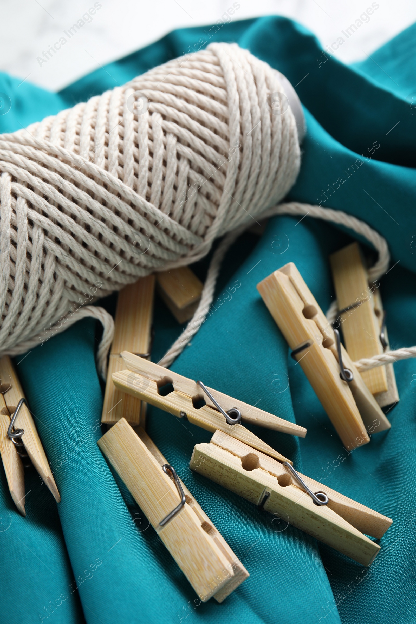 Photo of Many wooden clothespins and twine on teal fabric