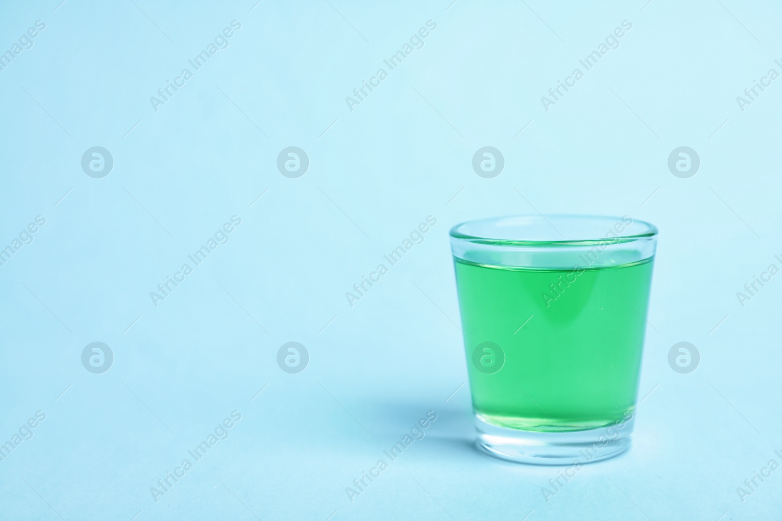 Photo of Glass with mouthwash and space for text on color background. Teeth hygiene