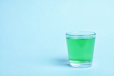 Photo of Glass with mouthwash and space for text on color background. Teeth hygiene