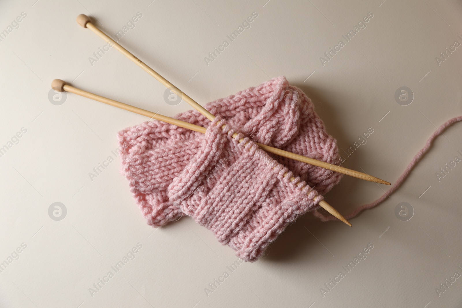 Photo of Pink knitting and needles on beige background, top view