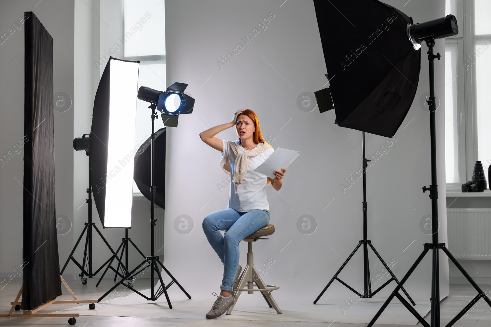 Photo of Casting call. Emotional woman with script performing on grey background in modern studio