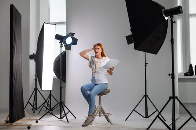 Casting call. Emotional woman with script performing on grey background in modern studio