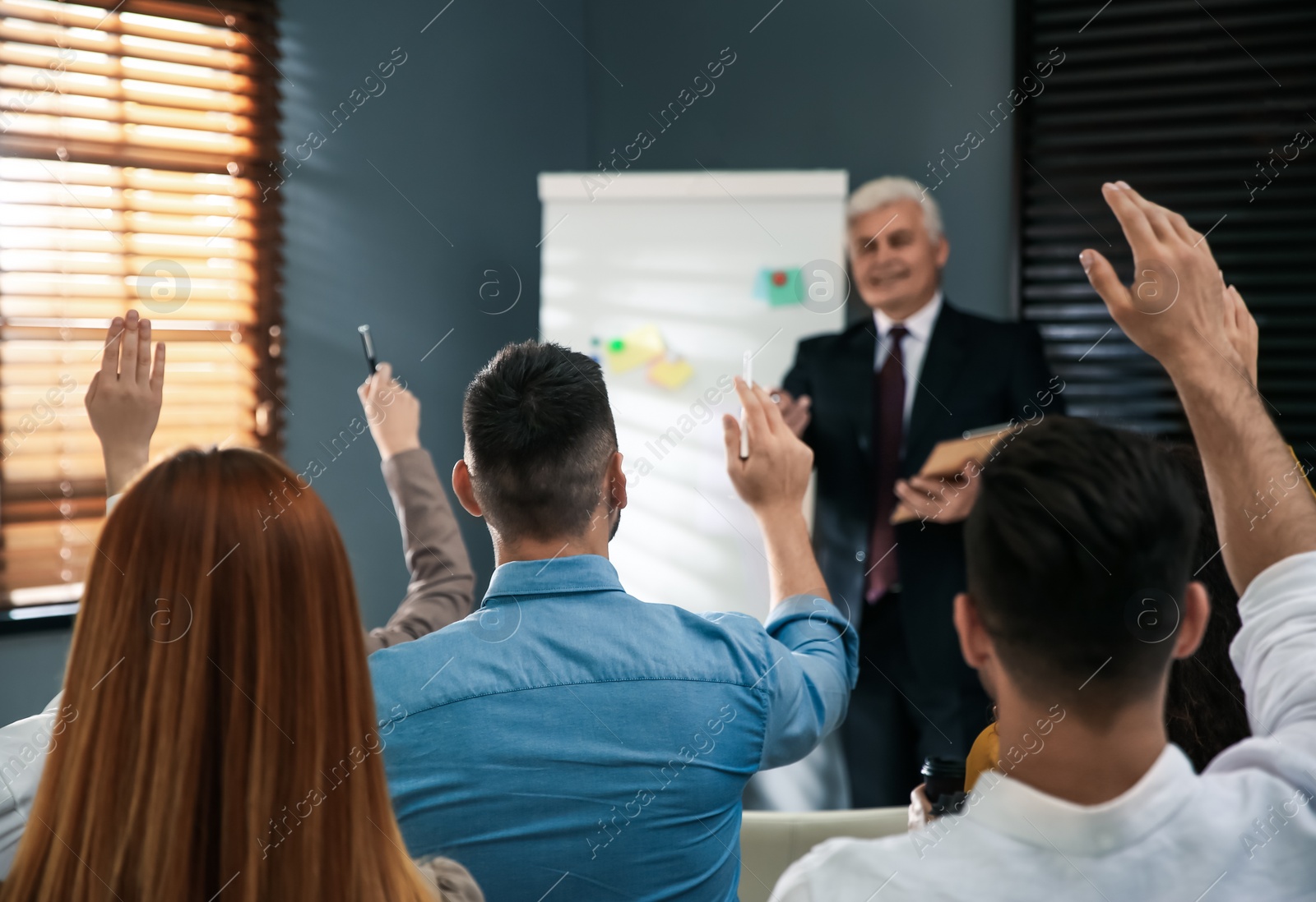 Photo of People raising hands to ask questions at seminar in office