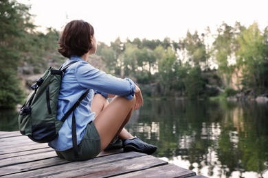 Young woman on wooden pier near lake. Camping season
