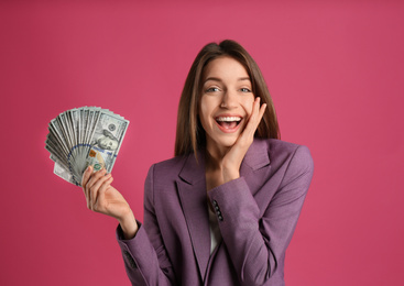 Happy young woman with cash money on pink background