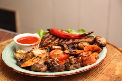 Photo of Plate with meat, garnish and sauce on wooden table in restaurant. Oven recipe