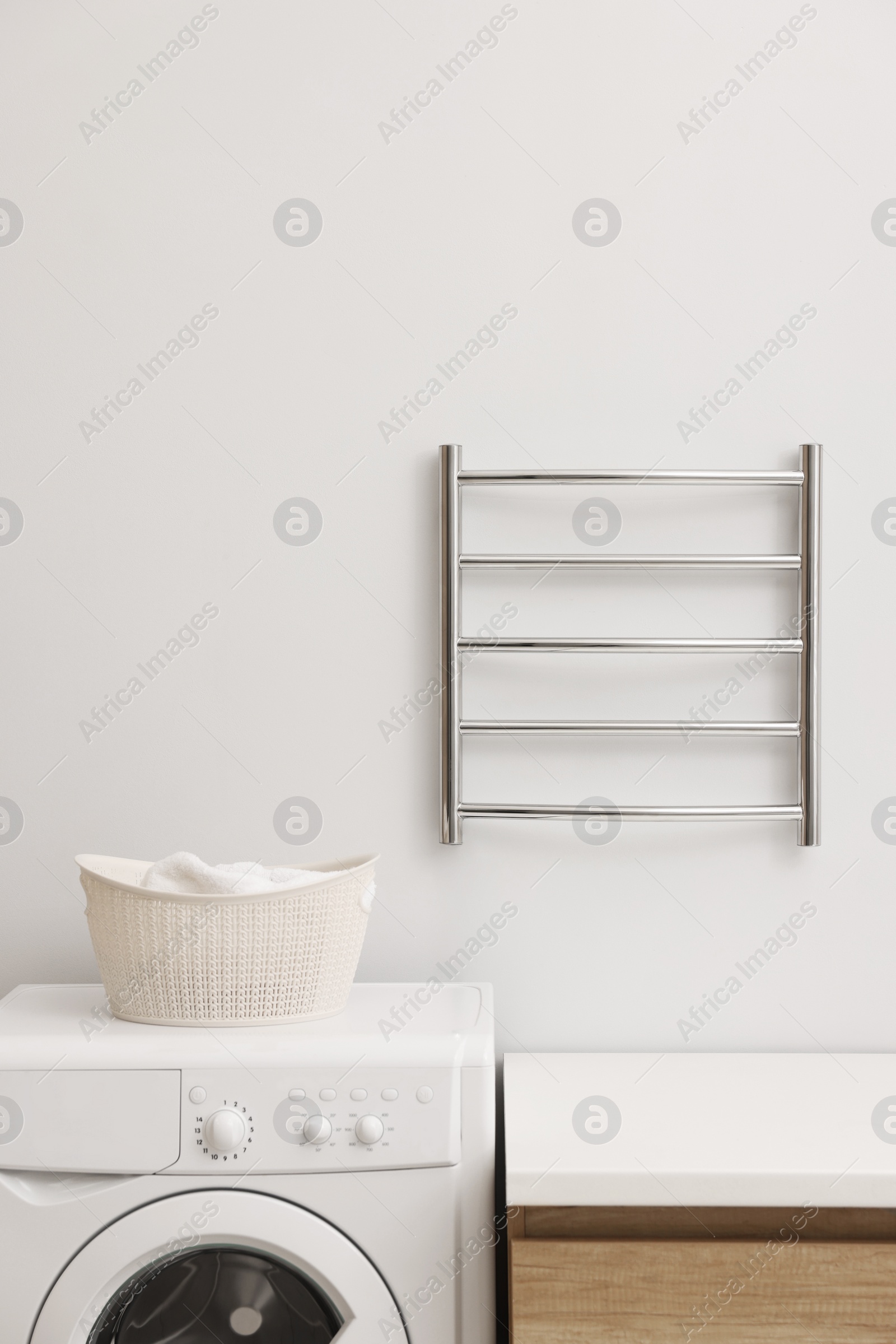 Photo of Stylish bathroom interior with heated towel rail and washing machine