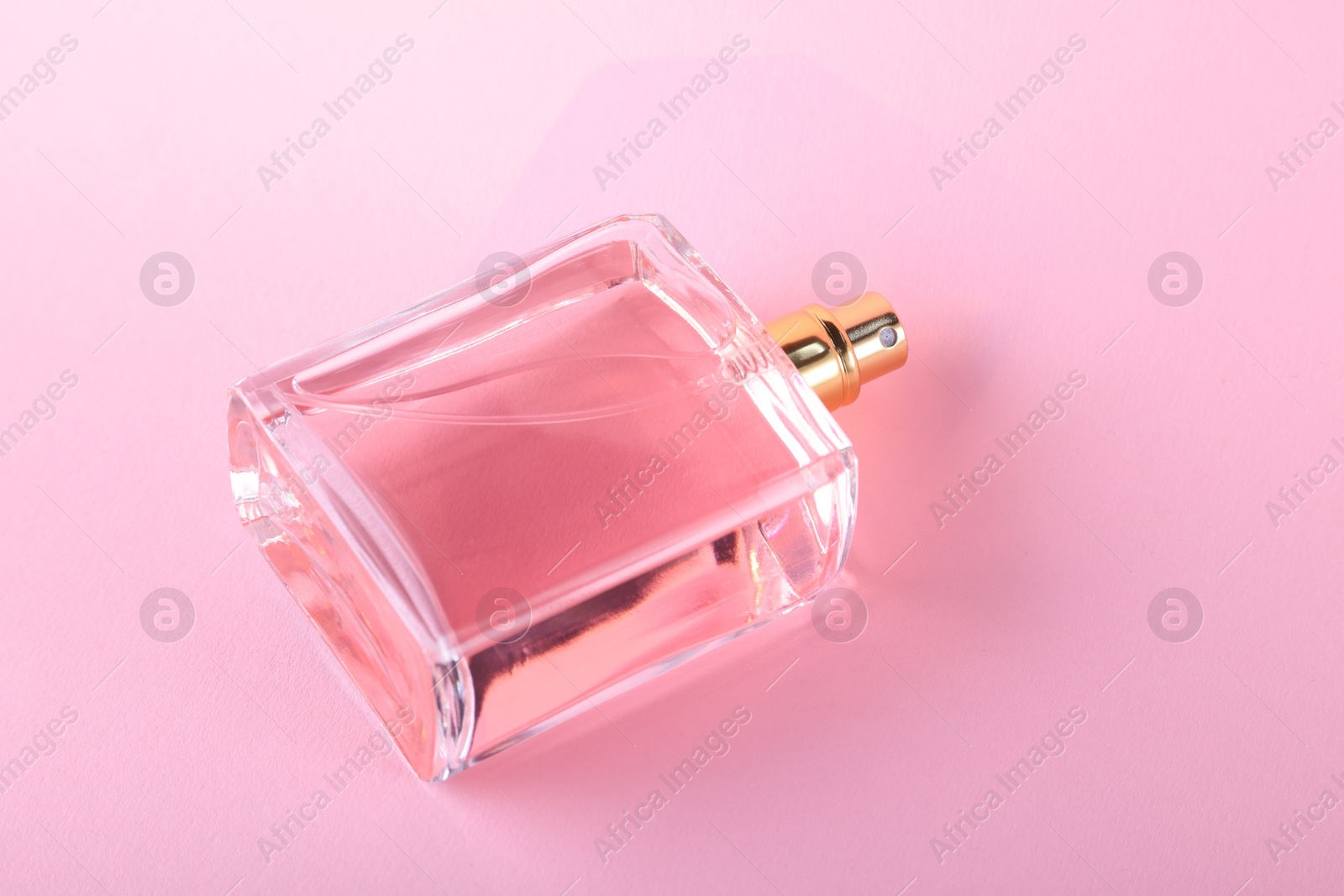 Photo of Luxury women's perfume in bottle on violet background