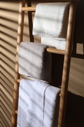 Photo of Terry towels on wooden decorative ladder near beige wall