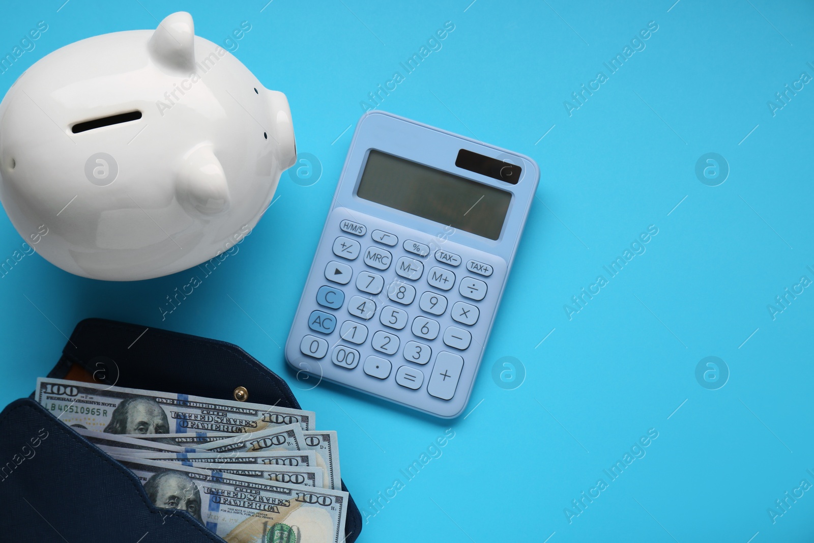 Photo of Piggy bank, calculator and wallet with banknotes on light blue background, flat lay. Space for text